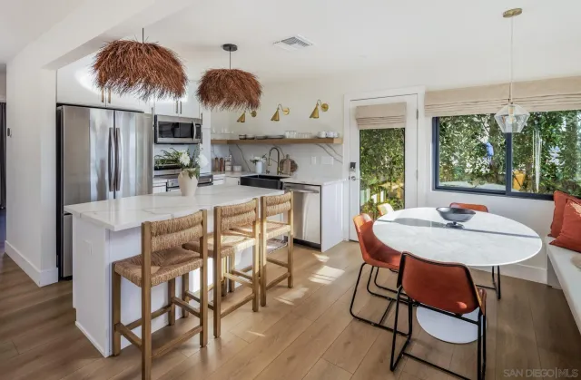 a kitchen with stainless steel appliances kitchen island granite countertop a table chairs and a refrigerator