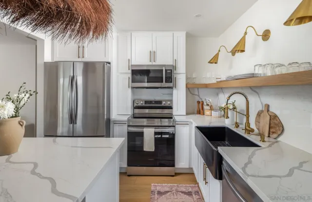 a kitchen with stainless steel appliances granite countertop a sink a stove and refrigerator