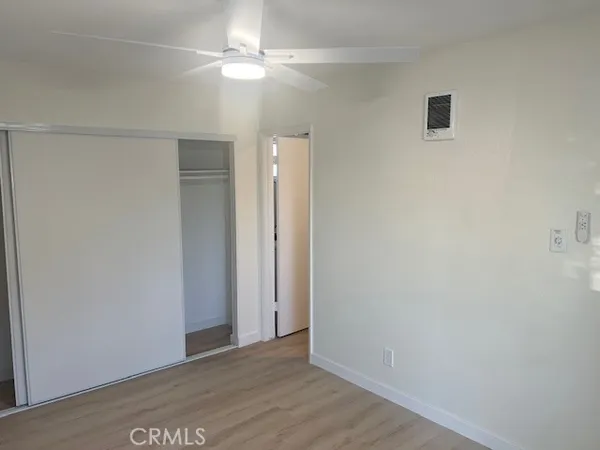 an empty room with wooden floor ceiling fan and window