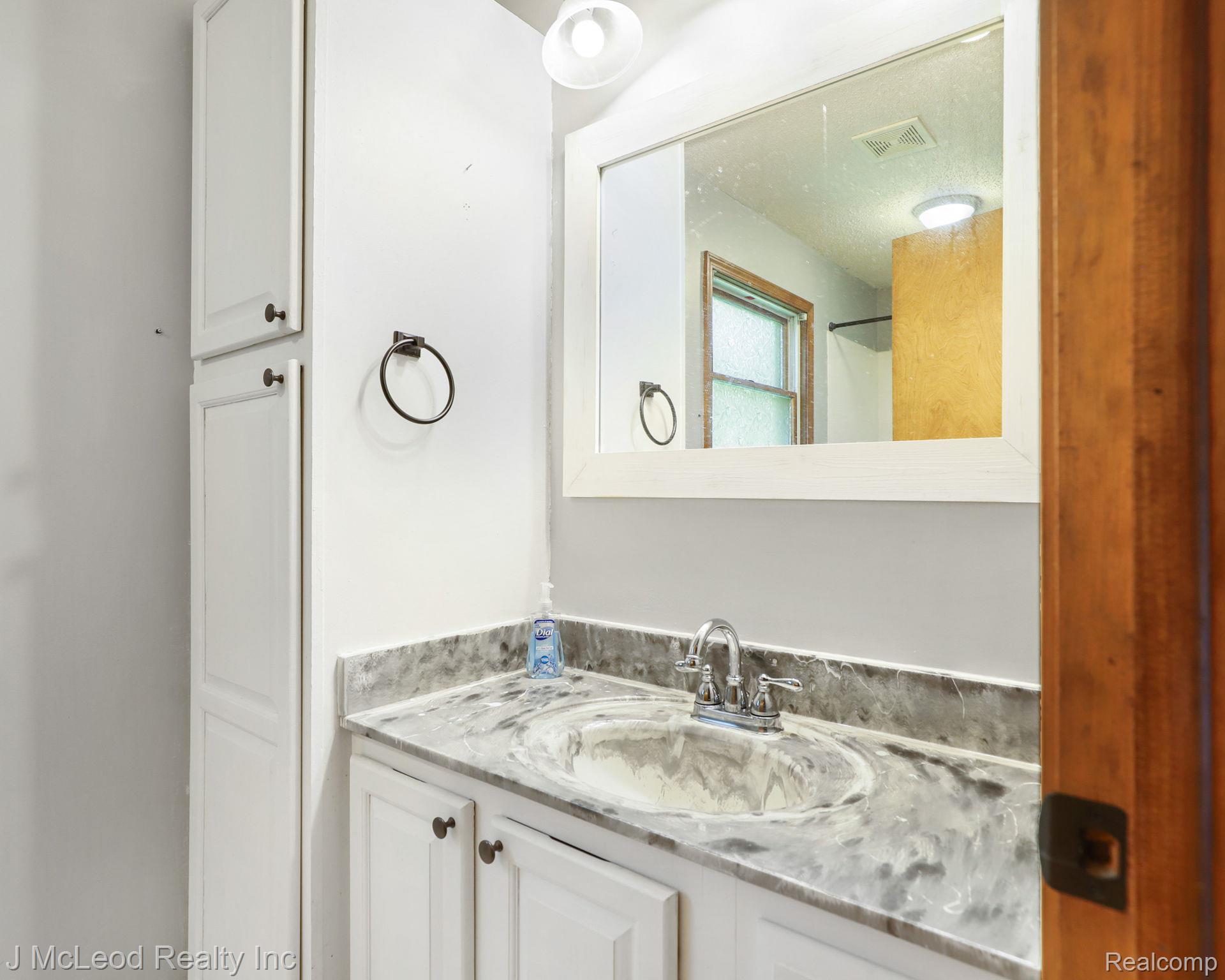 69 West Snover Road Mayville, MI 48744 - Photo 20 of 46 White vanity with a gray stone-finish countertop, undermount sink, and chrome faucet