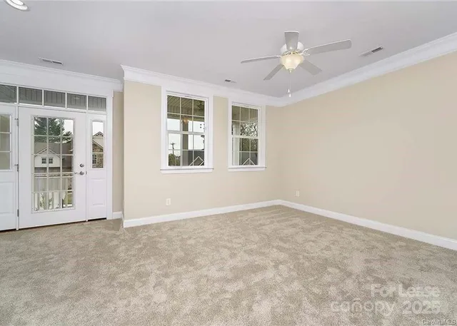 an empty room with windows and ceiling fan
