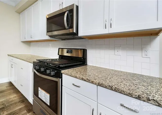 a kitchen with stainless steel appliances granite countertop white cabinets and a stove