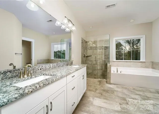 a bathroom with a granite countertop double vanity sink a bathtub and shower