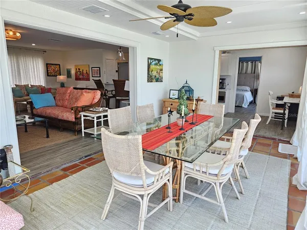 a dining room with wooden floor a chandelier fan a wooden table and chairs