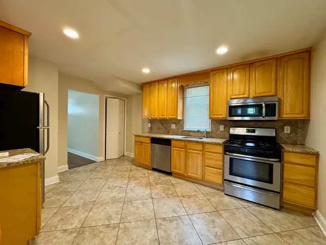 a kitchen with stainless steel appliances granite countertop a stove a sink and a microwave