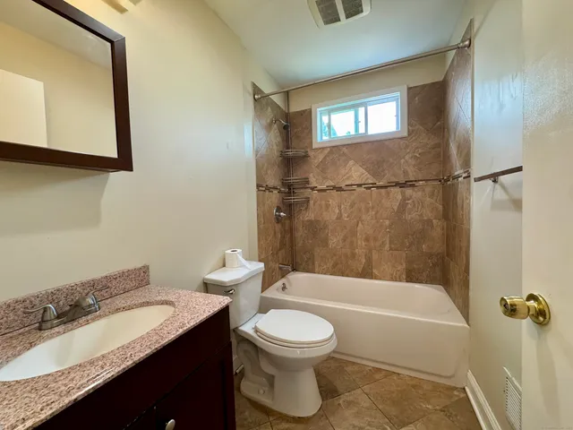 a bathroom with a granite countertop sink toilet a mirror and bathtub