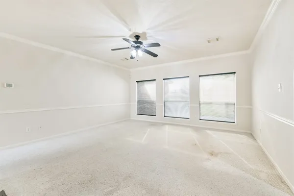 an empty room with chandelier fan and windows
