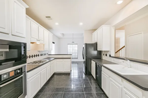 a kitchen with stainless steel appliances granite countertop a sink and dishwasher a stove top oven with white cabinets