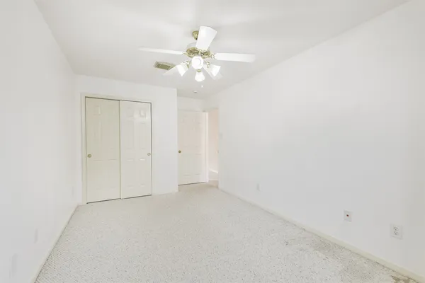 an empty room with a chandelier fan and closet