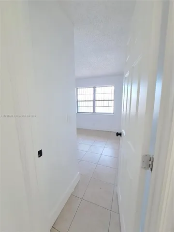 a view of an empty room with window and hardwood floor