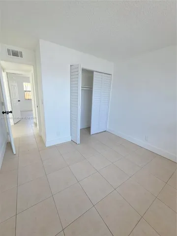a view of an empty room and a bathroom with sink