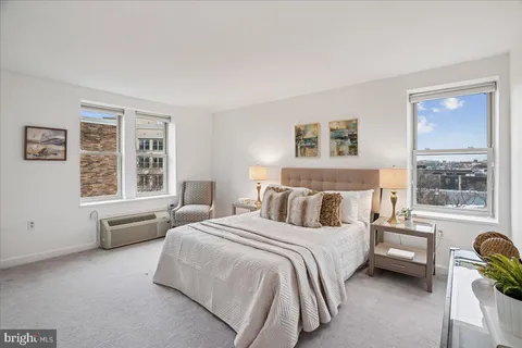 a bedroom with a bed a couch and large window