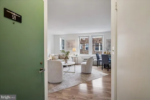 a living room with couches a coffee table and a potted plant with wooden floor