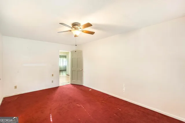 an empty room with a chandelier fan and windows