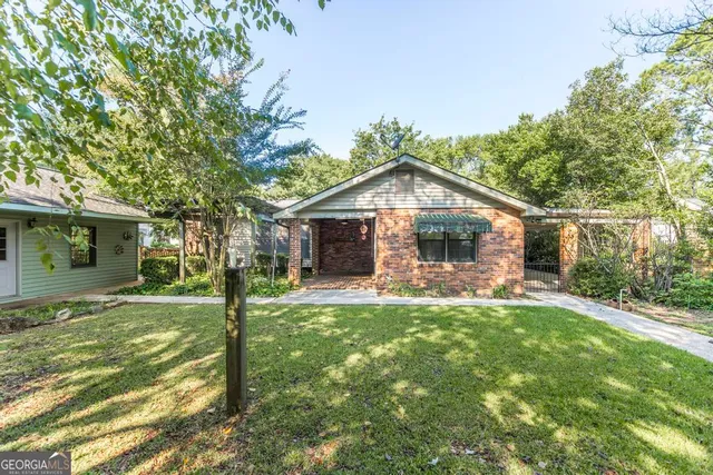 a front view of a house with a garden and trees