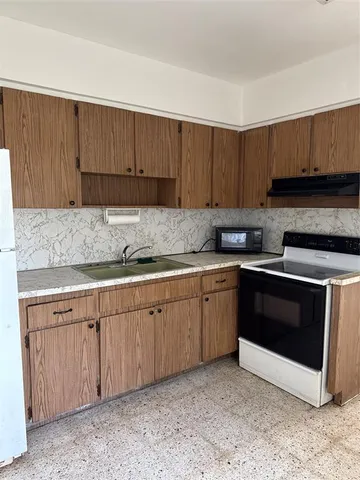 a kitchen with granite countertop a sink cabinets and stainless steel appliances