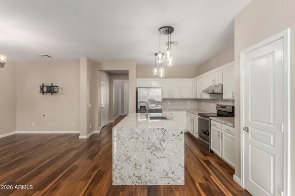 a large kitchen with kitchen island white cabinets and stainless steel appliances