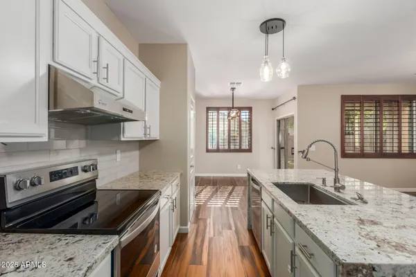 a kitchen with stainless steel appliances granite countertop a sink a stove and a refrigerator