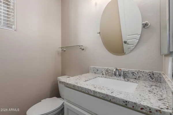 a bathroom with a granite countertop sink a toilet and mirror