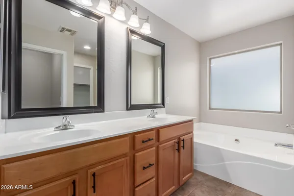 a bathroom with a sink double vanity granite tub and a mirror