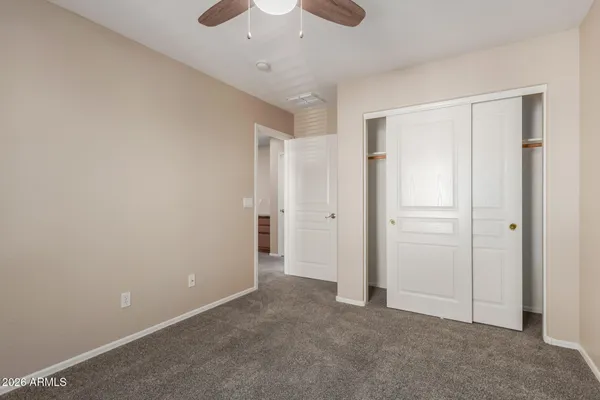 an empty room with a ceiling fan and closet area