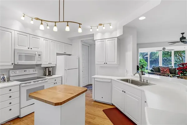 a kitchen that has a sink a stove and a oven with white cabinets