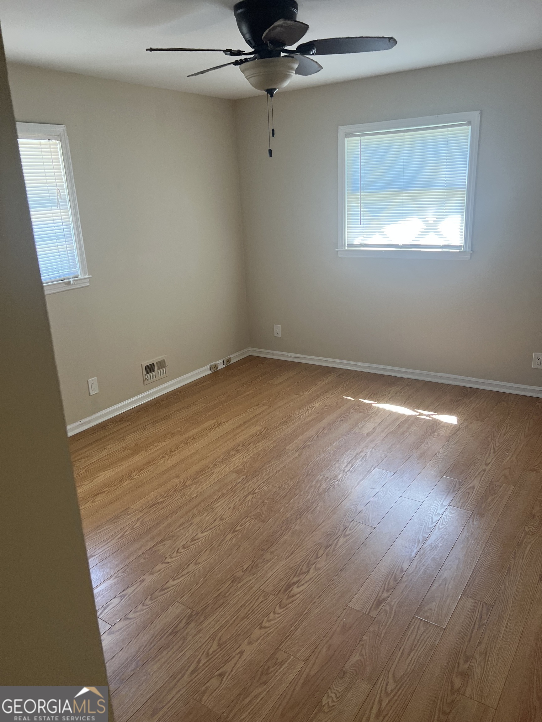 4910 Thompson Mill Road Lithonia, GA 30038 - Photo 24 of 28 an empty room with a wooden floor and a ceiling fan