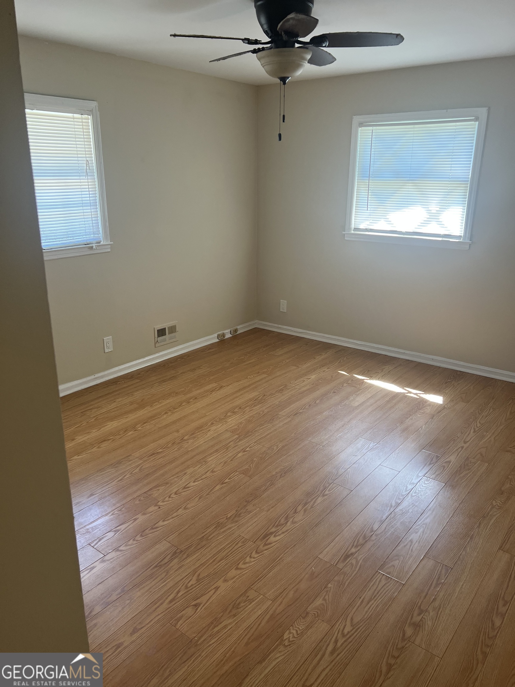 4910 Thompson Mill Road Lithonia, GA 30038 - Photo 25 of 28 an empty room with a wooden floor and windows