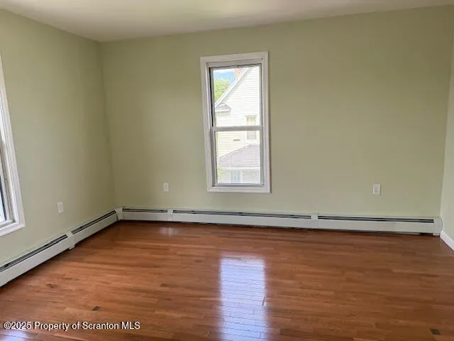 an empty room with wooden floor and window