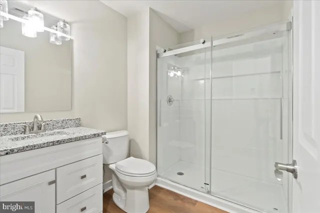 a bathroom with a granite countertop sink toilet a mirror a glass door shower and vanity