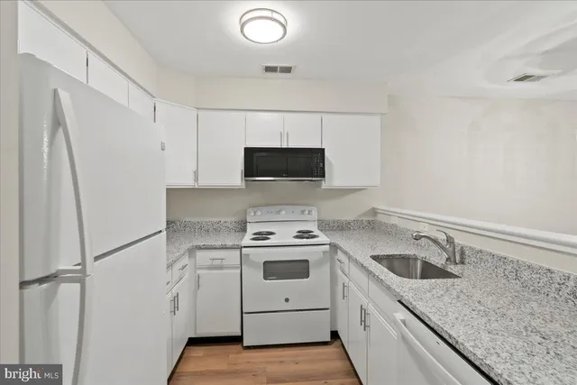 a view of a kitchen with white cabinets and white appliances