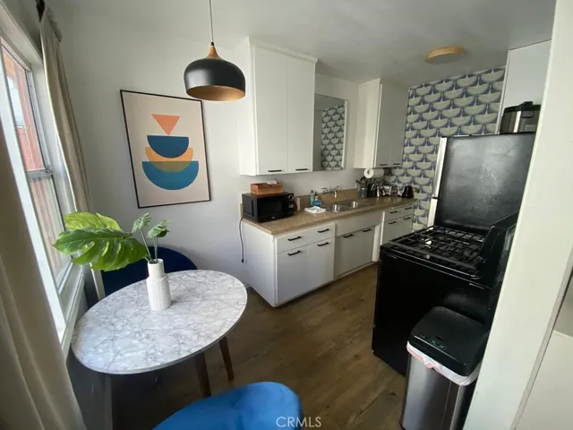 a kitchen with stainless steel appliances granite countertop a sink a stove a refrigerator a dining table and chairs