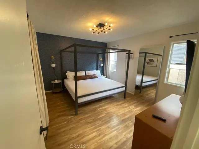 a spacious bedroom with a bed and a dresser next to a window