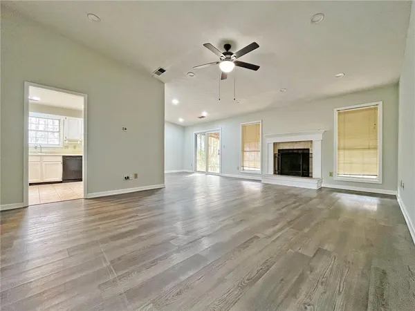 a view of an empty room with window and wooden floor