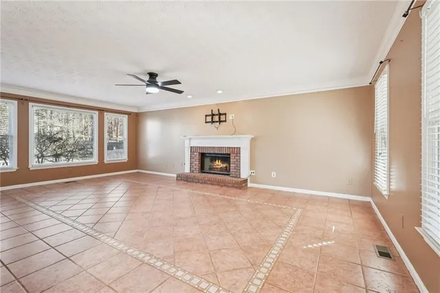 an empty room with wooden floor chandelier and windows