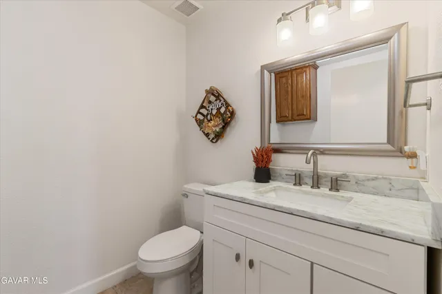 a bathroom with a granite countertop toilet sink mirror and vanity