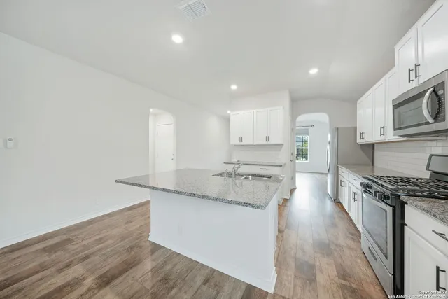 a large kitchen with stainless steel appliances granite countertop a stove a sink and a refrigerator