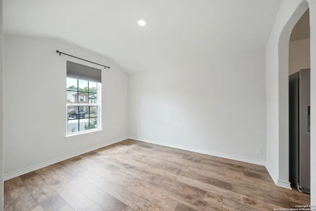 a view of an empty room with wooden floor and a window
