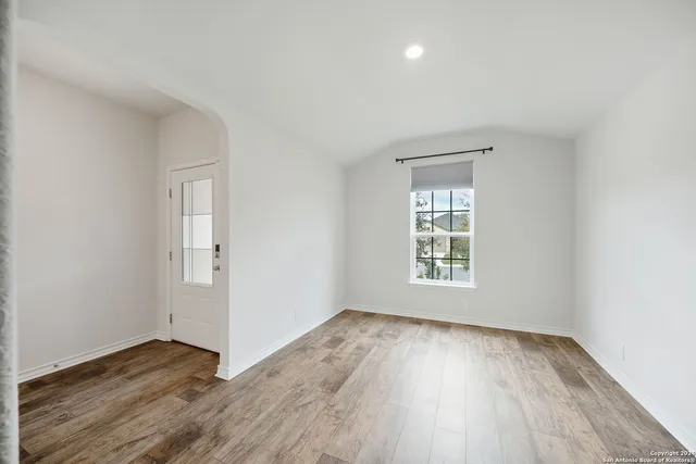 an empty room with wooden floor and windows