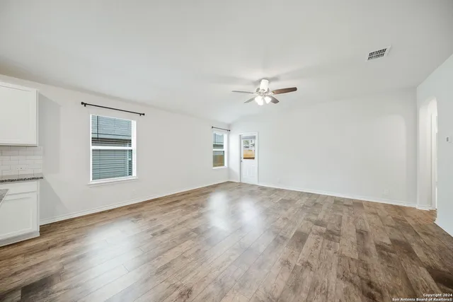 a view of empty room with wooden floor and fan