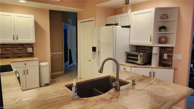 a living room with stainless steel appliances kitchen island granite countertop a refrigerator and a stove top oven