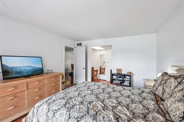 a bedroom with a bed and flat tv screen on the dresser