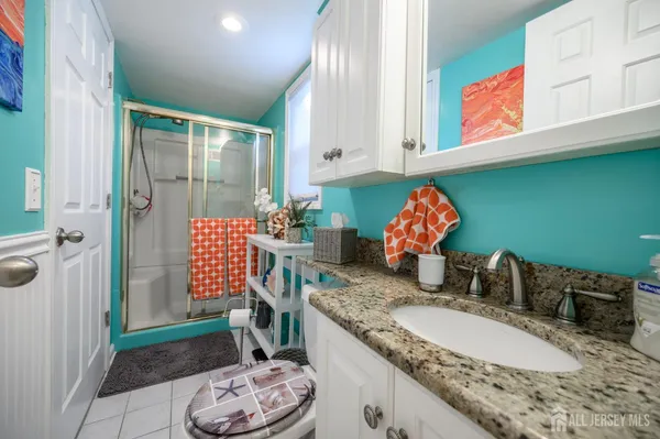 a bathroom with a granite countertop sink a mirror and shower