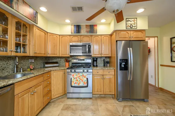 a kitchen with stainless steel appliances granite countertop a refrigerator a stove and a sink