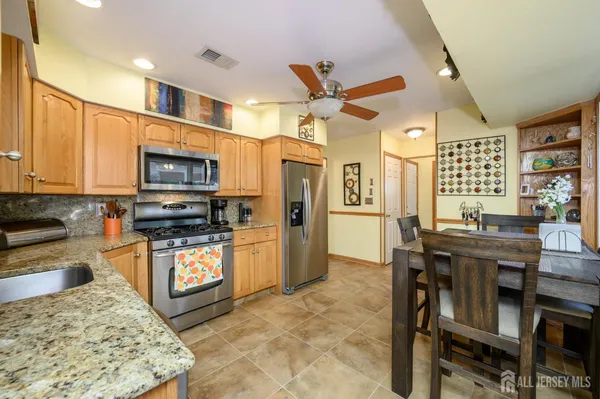 a kitchen with stainless steel appliances kitchen island granite countertop a refrigerator a stove top oven and a dining table