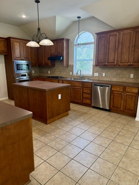 20724 Kearney Hill Road Pflugerville, TX 78660 - Photo 17 of 40 Kitchen featuring rich wood cabinetry, stainless steel appliances, a center island, tile flooring, and a vaulted ceiling