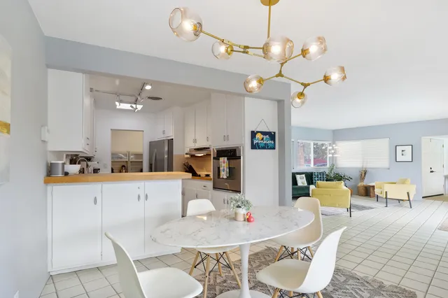 a living room with furniture kitchen view and a chandelier