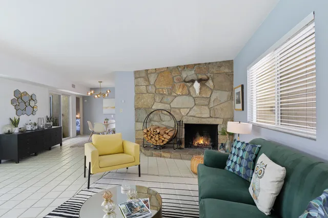 a living room with furniture a fireplace and a large window