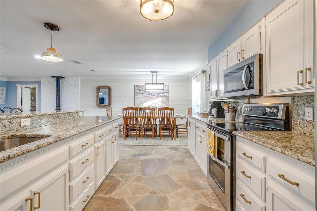 520 Deer Trail Gordon, TX 76453 - Photo 5 of 40 Kitchen with stainless steel appliances, stone flooring, light stone counters, and white cabinets