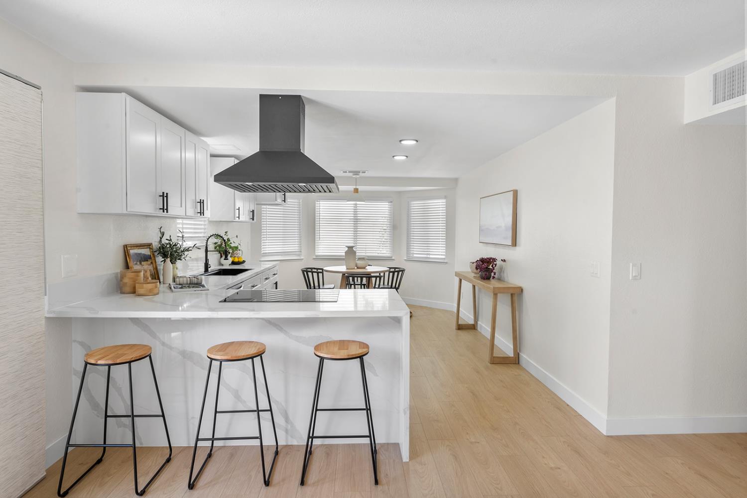 7531 Event Way Sacramento, CA 95842 - Photo 6 of 36 kitchen featuring a kitchen bar, range hood, laminate floors, a peninsula, and quartz countertops with waterfall